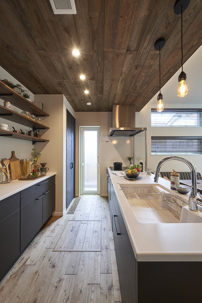 ［埼玉県所沢市］ダブル断熱仕様のZEH（ゼロエネルギーハウス）ヤマト住建モデルハウスの木目調の天井の落ち着いた色合いのキッチン